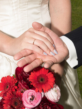 Couple Showing Wedding Rings Over Floral Bouquet