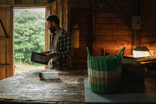 Rural worker holding tool entering rustic shed