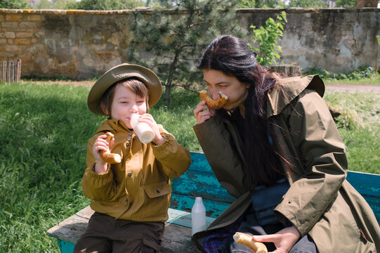 Mother and son enjoying a snack together on a park bench