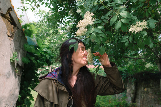 Woman smelling blossoms on a flowering tree in a park