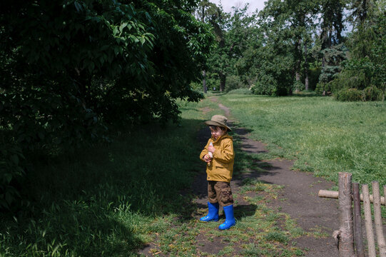Young boy standing on a park pathway surrounded by greenery