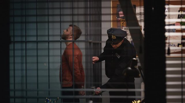 Police officer opening a jail cell to transfer a male detainee to prison