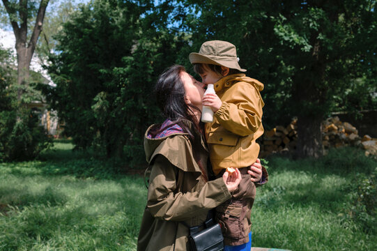 Mother embracing her son in a park surrounded by trees