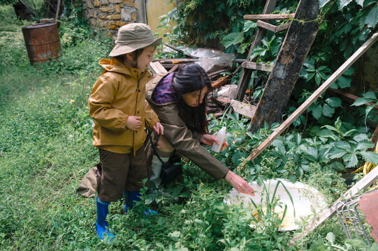 Mother and son observing a lizard in garden water basin after rain