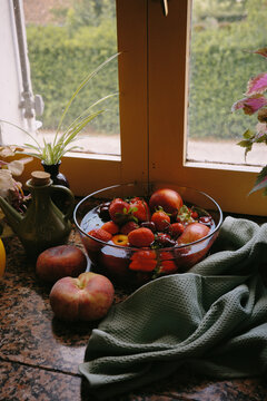 Fresh fruits are arranged on a kitchen countertop near a window