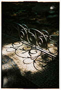 Ornamental Iron Fence Casting Shadows on Mosaic Pavement