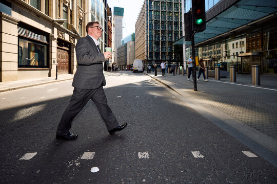 Businessman walks across the street in central London