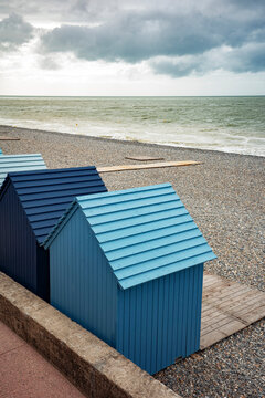 Beach Huts Stand by the Ocean Under Cloudy Skies at the Coast