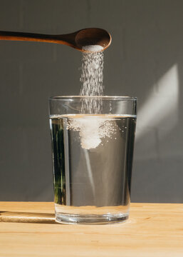 Spoon Adding White Supplement Powder to Water
