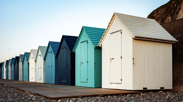 Beach Huts Line the Coast at Sunset Near a Rocky Shore