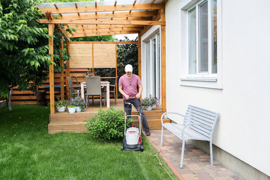 A man mows the lawn in the yard.