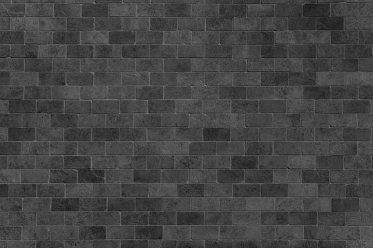 Dark gray stone wall with handmade rectangular bricks. Textured charcoal masonry surface with monochrome shades for a vintage background.