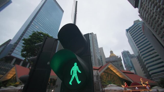 A close-up of a traffic light showing a green signal for pedestrians an urban landscape with road traffic where crossing is permitted.