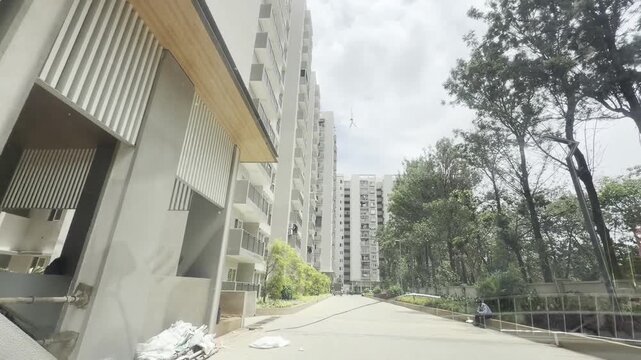 Full HD drive through modern apartment complex with tall residential towers, balconies, green landscaping and quiet internal road under cloudy daylight, showing urban housing and gated community life.
