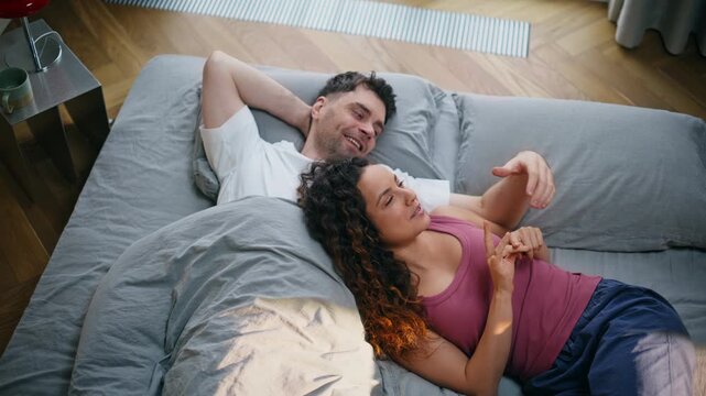 Loving couple cuddling bed morning. Woman resting boyfriend shoulder cozy home.