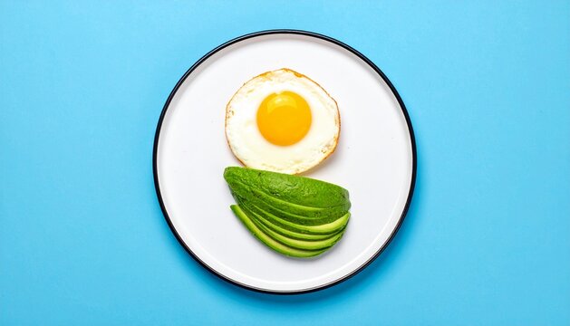Healthy Breakfast Fried Egg and Sliced Avocado on Plate, Blue Background