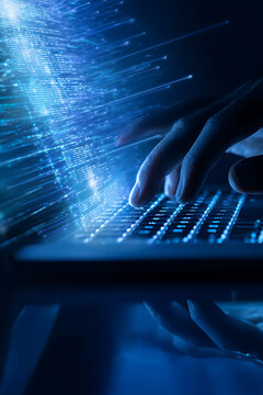 Close-up of a persons hands typing on a laptop keyboard with glowing blue fiber optic lights.