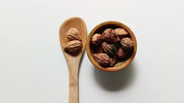 Dry seeds of hicaco fruit of Chrysobalanus icaco inside a small rustic clay bowl and on a wooden bamboo spoon for typical traditional dish from Guatemala