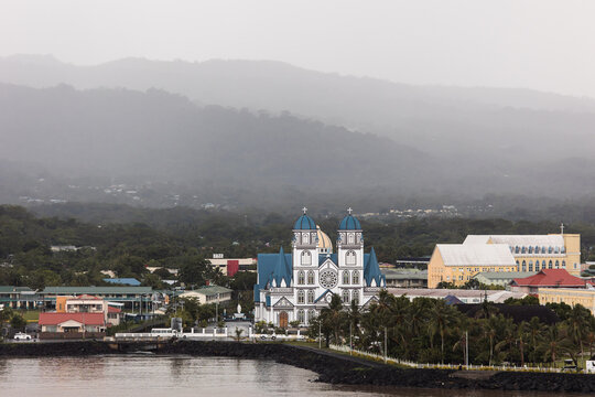 Apia's church spires and buildings viewed against misty mountains, Samoa