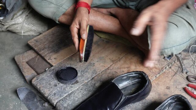 Cobbler polishing black leather shoe with care
