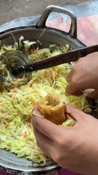 Hands stuffing fried tofu with vegetable mix for Indonesian Tahu Isi snack
