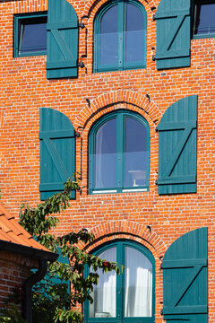 Historic maritime architecture and red brick wall with green shutters at the canal port in Kiel-Holtenau vertical view