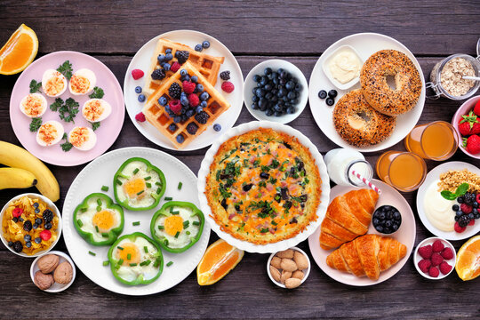 Breakfast or brunch table scene on a dark wood background. Top view. Assortment of fruits and sweet and savory food items.