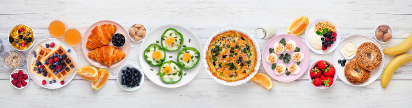 Breakfast or brunch table scene on a white wood banner background. Overhead view. Assorted fruits and sweet and savory food items.