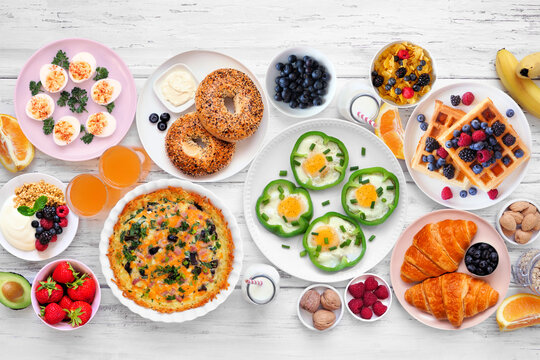 Breakfast or brunch table scene on a white wood background. Top down view. Variety of fruits and sweet and savory food items.