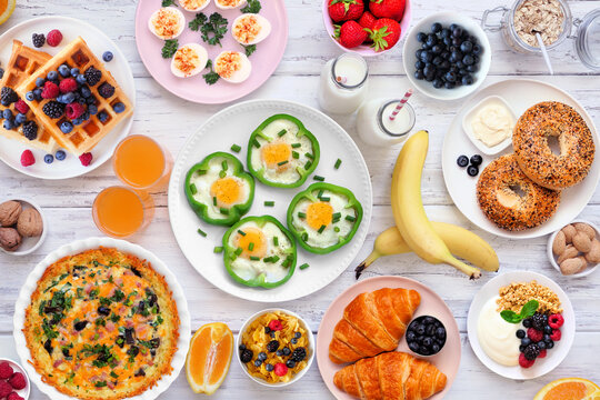 Breakfast or brunch table scene on a white wood background. Above view. Assorted fruits and sweet and savory food items.