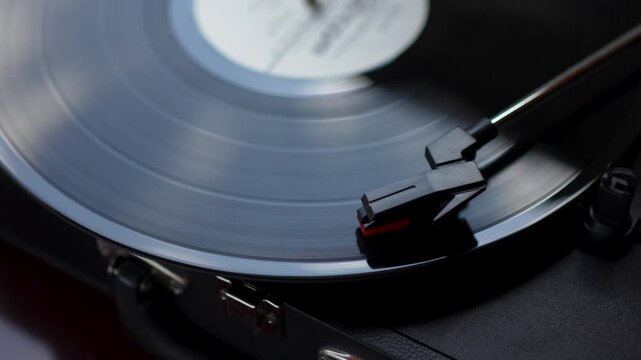 Vinyl record spinning on turntable with needle cartridge close up.