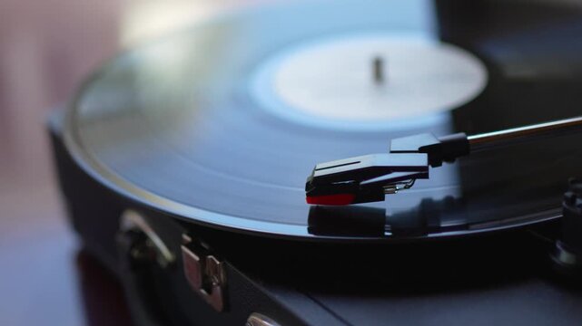 Vinyl record spinning on turntable with needle cartridge close up.