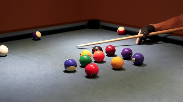 Billiard player in glove aiming cue at white cue ball close up.