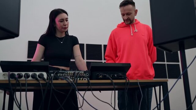 DJs collaborating in large white studio mixing music on DJ controllers and turntables. DJ, collaboration, studio, music, controllers, turntables