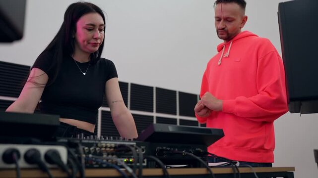 DJ trainer correcting student's hand placement on mixer during club music lesson. DJ, trainer, hand placement, mixer, lesson