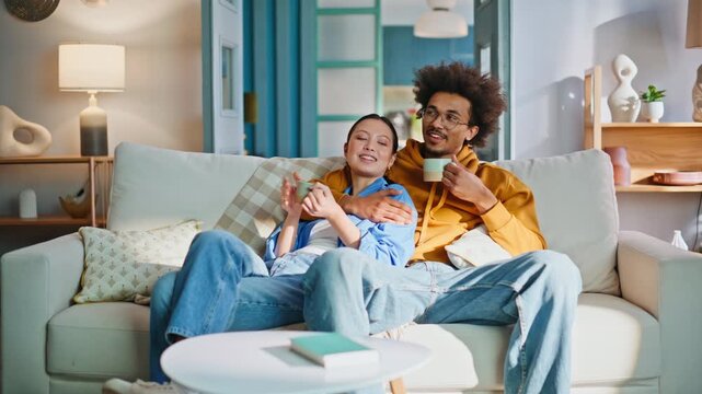 Affectionate couple drinking coffee on sofa at home. Closeup relaxing weekend.