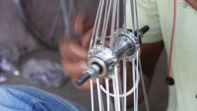 Person lacing bicycle wheel spokes with precision