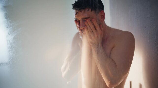 Young man taking hot shower washing head under water. Morning routine closeup