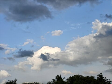 Blue sky with contrasting bright white cumulus and dark rain clouds