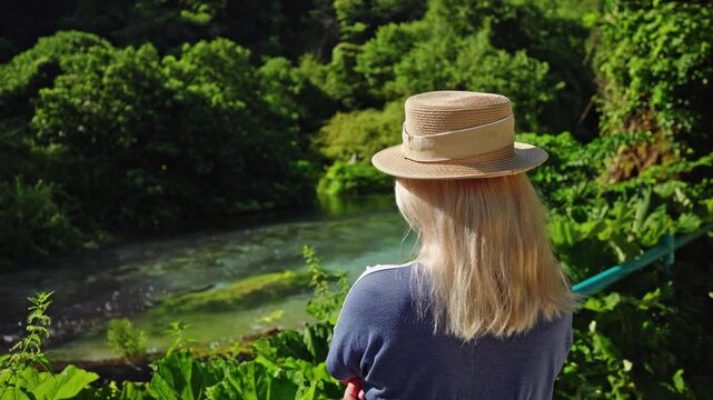 Woman in straw hat overlooking Blue Eye spring in Albania