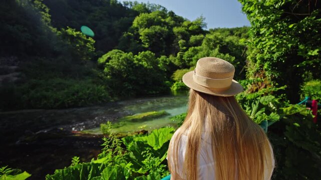 Woman in straw hat admiring Blue Eye spring in Albania
