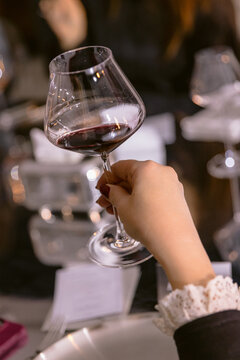 Woman holding glass of red wine during dinner tasting at luxury restaurant