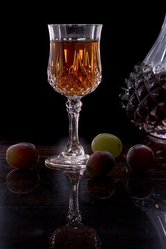 Elegant crystal glass filled with amber vermouth next to traditional Spanish gildas with green olives and anchovies on a dark reflective surface