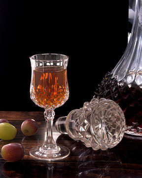 Elegant crystal glass filled with amber vermouth next to traditional Spanish gildas with green olives and anchovies on a dark reflective surface