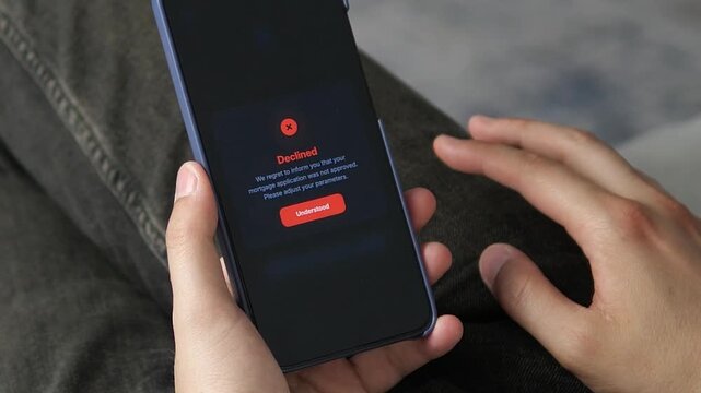 User viewing a declined mortgage notification on a mobile banking app. Essential footage for stories on the housing affordability crisis, rising rates, and lending freezes.