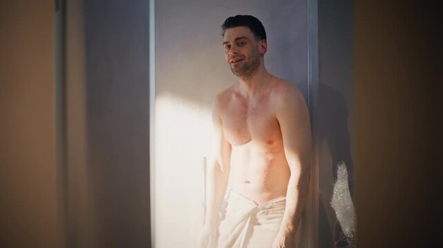 Handsome man wrapped towel after shower laughing in bathroom. Wet body morning