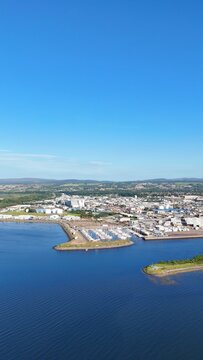 Wide distant view of Inverness, Scotland, British Highlands, revealing the river, green lands, sea edge, and cloudy daytime scenery.