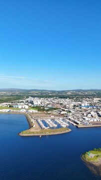 Distant view of Inverness in Scotland, British scenery showing the river, expansive green lands, sea waters, and calm cloudy skies.