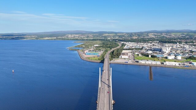 Inverness, Scotland, British city at daytime shows half water and half land, with a bridge, sea, clouds, and Highland scenery.