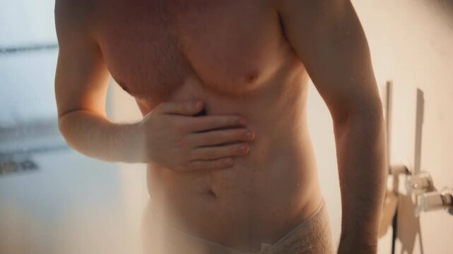 Shirtless man taking shower home bathroom. Closeup wet muscular body portrait.